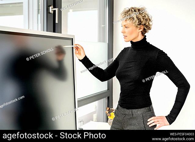 Businesswoman pointing on interactive whiteboard with digitized pen