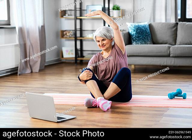 happy woman with laptop exercising at home