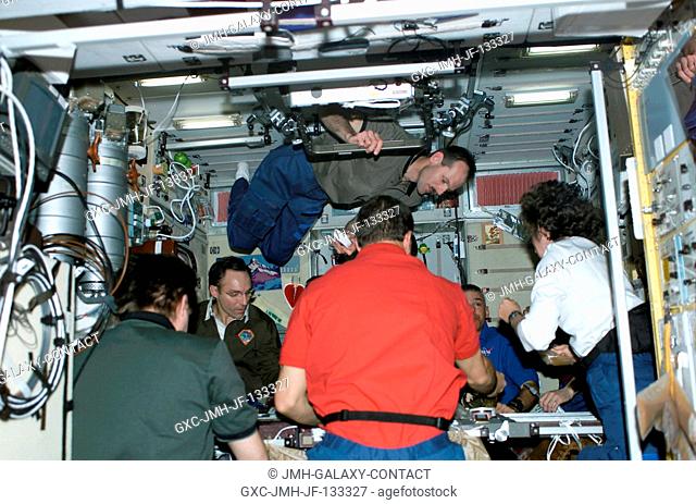 The STS-110 and Expedition Four crewmembers share a meal in the Zvezda Service Module on the International Space Station (ISS)