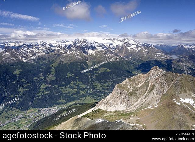 aerial shot, from a sailplane, of Sperella peak rocky summit with Poschiavo valley and Bernina range and lake in background