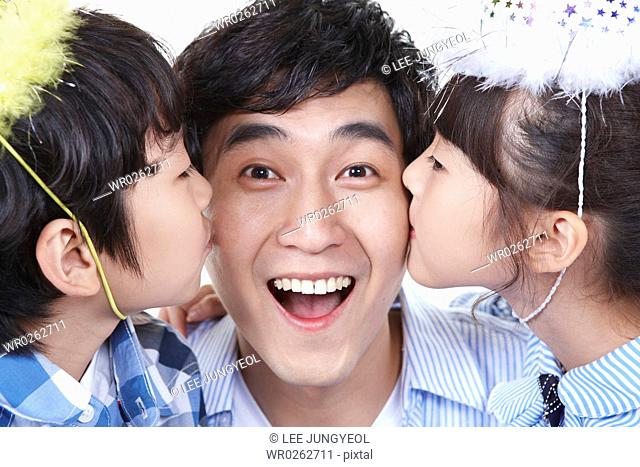 boy and girl kissing father's cheek