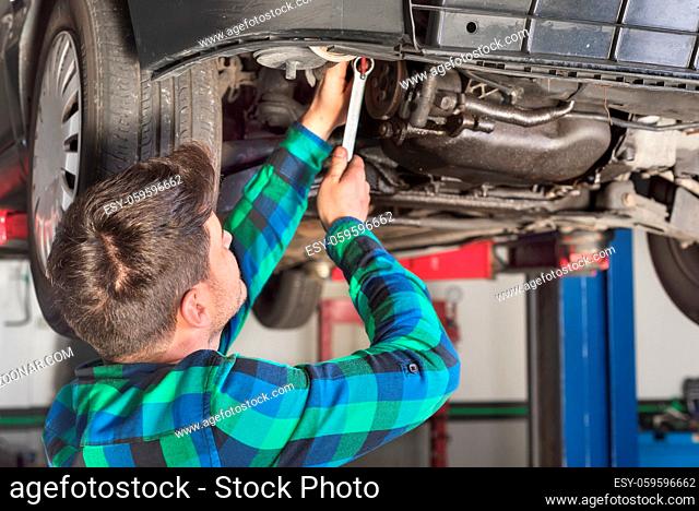Portrait of mechanic repairing with a wrench a lifted car