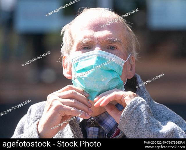 22 April 2020, Saxony, Dresden: A resident of the Elbflorenz senior citizens' home in Dresden sits outside with a mouth guard
