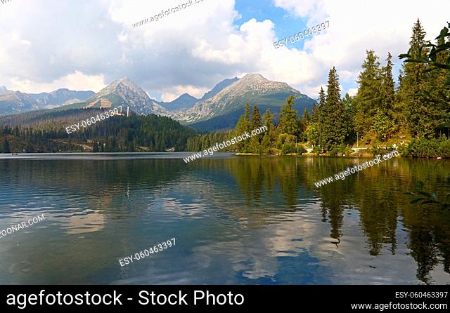 Beautiful tranquil rural scene landscape with mountain lake Strbske Pleso and forest under cloudy blue sky, Tatra, Slovakia