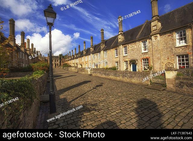 View down the ancient Vicar&#39;s close lane in Wells, Somerset, England in sunshine and puffy clouds