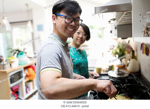 Portrait smiling couple cooking at stove in kitchen