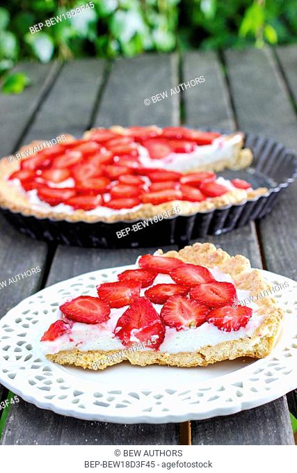 Strawberry cake on wooden tray in summer garden. Festive and party dessert