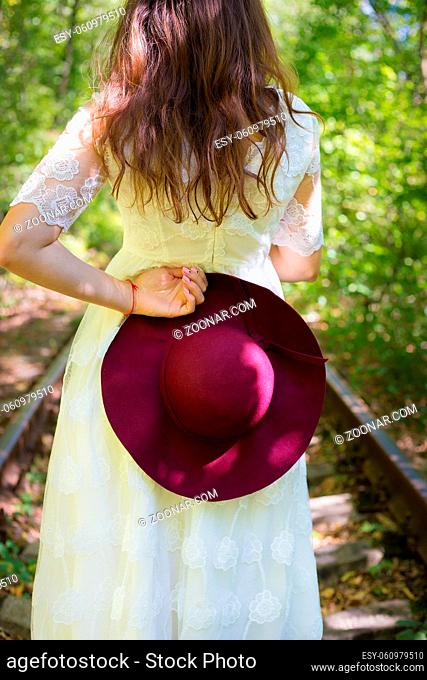 A girl in a white dress with cherry hat in the woods