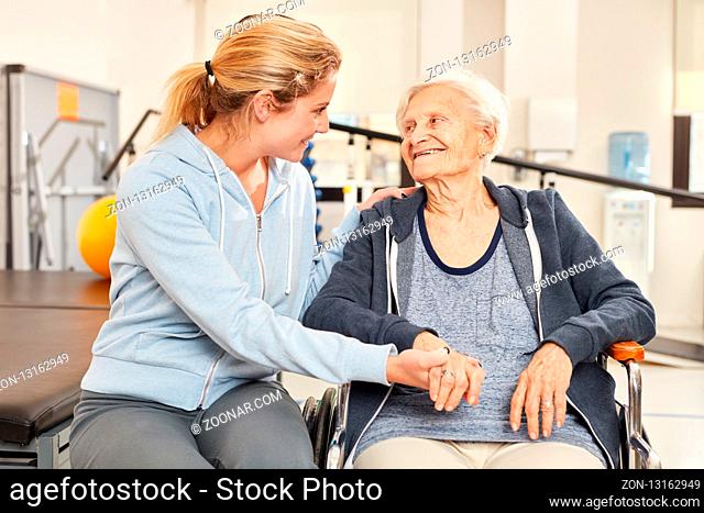 Fürsorgliche Trainerin betreut eine Senior Frau im Rollstuhl bei der Physiotherapie