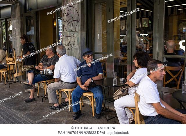 04 July 2019, Greece, Athen: People sit in a café next to the Varvakios market hall. On Sunday the Greek voters are likely to reject extreme parties in the...