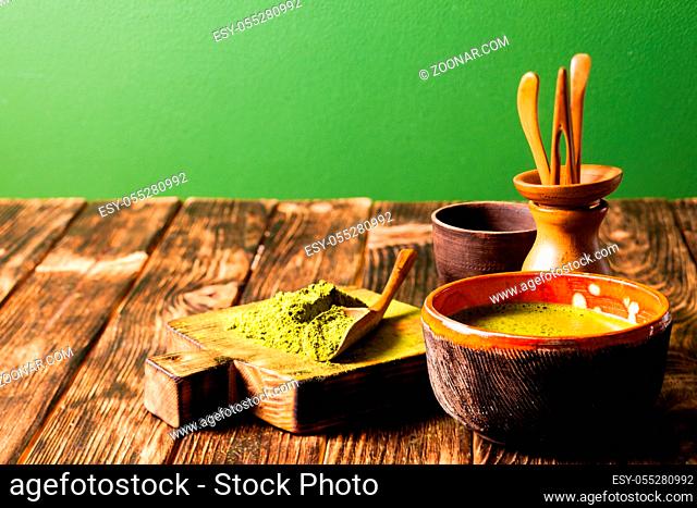 Matcha powdered tea heap and matcha drink in a bowl on the table, copy space