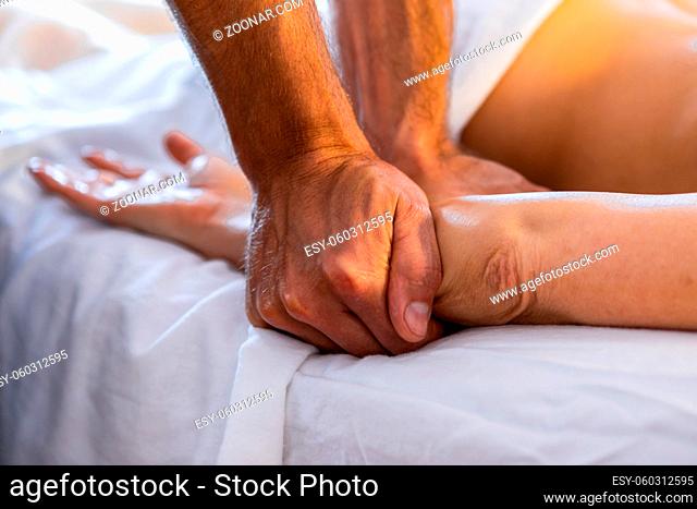 Close-up view of professional masseur-therapist natural massage. The masseur makes a hand massage to a woman in a cosy home environment