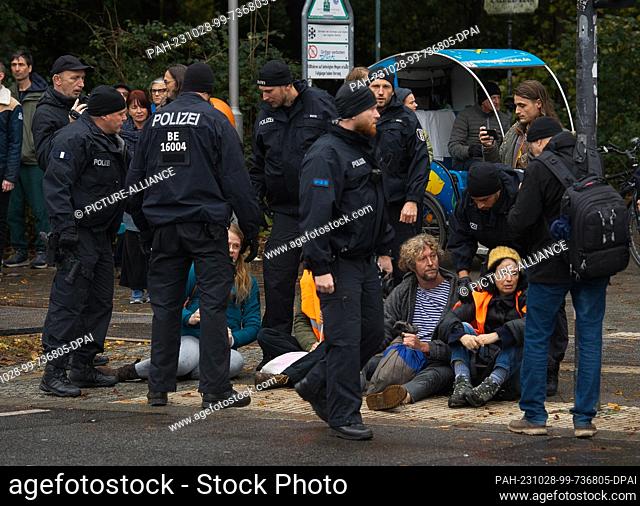 28 October 2023, Berlin: Police officers stand by a group of environmental activists on the street of June 17. Environmental activists had called on the net for...