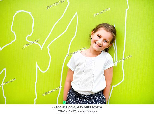 Smiling little girl child on light green background. Concept of family happiness