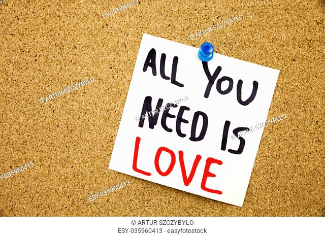 Phrase ALL YOU NEED IS LOVE in black ext on a sticky note pinned to a cork notice board