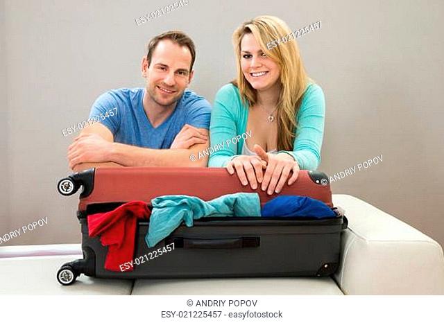 Portrait Of Happy Couple Leaning On Suitcase