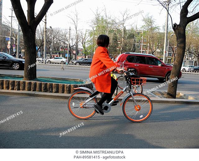 A woman rides a bicycle of the rental bike company 'mobike' on a street in Beijing, China, 28 March 2017. Photo: Simina Mistreanu/dpa | usage worldwide