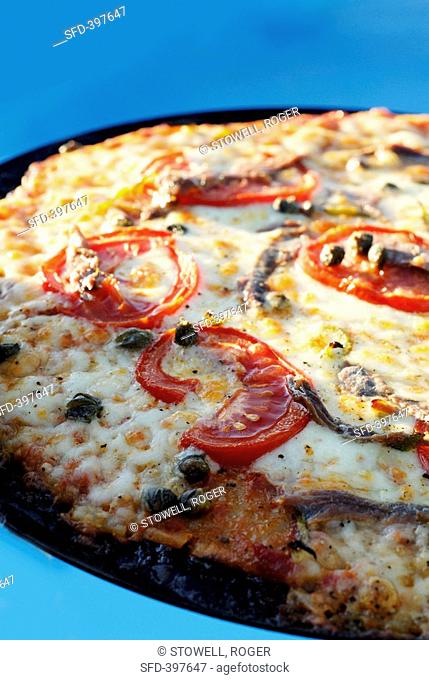 Pizza topped with tomatoes, capers and anchovies detail