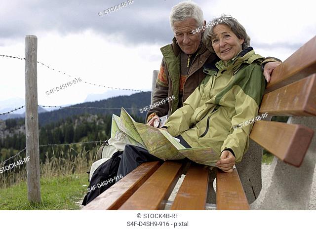 Old married couple looking at a map in the mountains