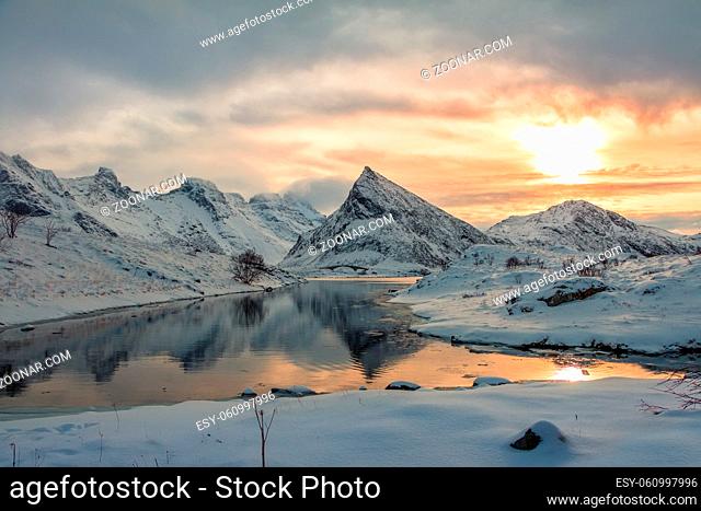 Small bay of the Norwegian fjord surrounded by snow-capped mountains. Winter evening