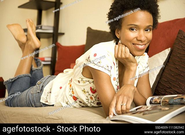 Woman laying on sofa and reading book