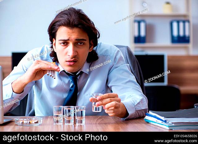 The male employee drinking vodka and smoking cigarettes at workplace