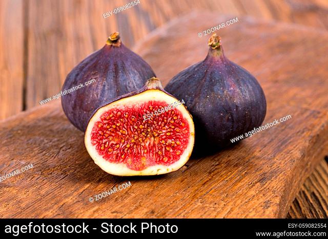 Two whole and one half delicious and sweets figs on a rustic wooden background