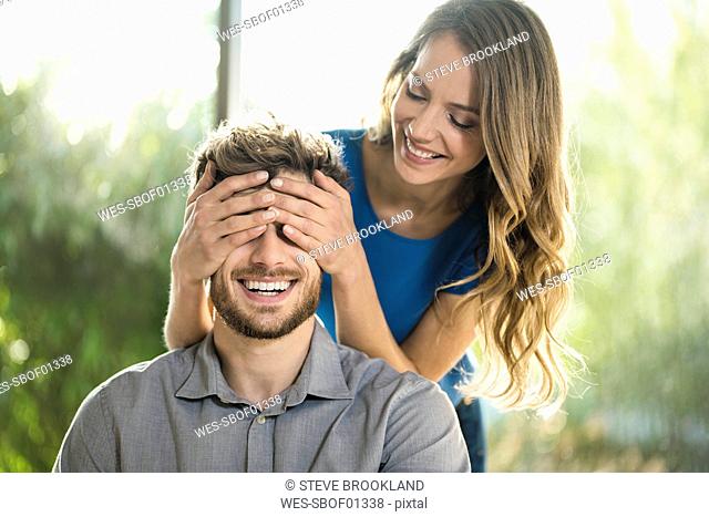 Smiling woman covering her boyfriend's eyes
