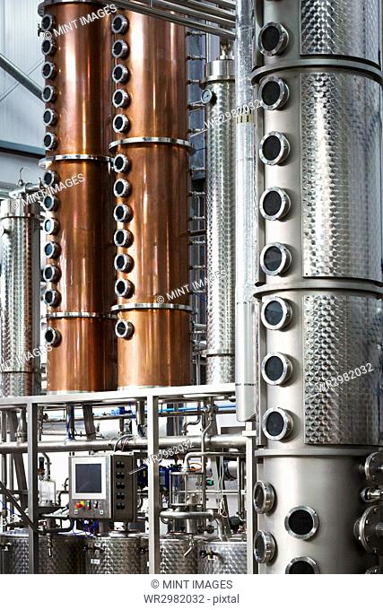 Tall copper distillery chambers in a brewery, brewing storage tanks in copper and steel