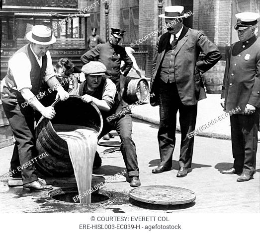 New York City Deputy Police Commissioner John A. Leach, right, watching agents pour liquor down a manhole following a raid during prohibition 1921