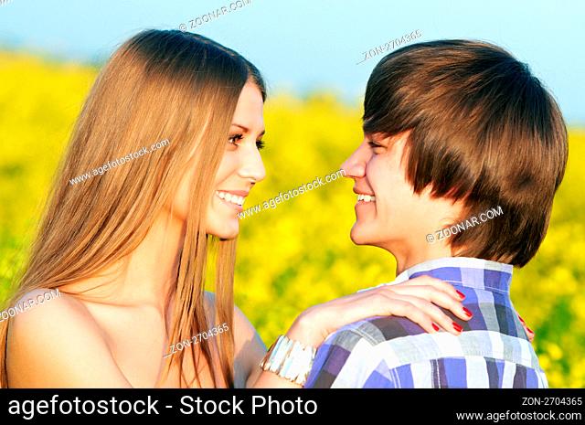 Happy smiling young couple embracing each other over yellow green rape meadow