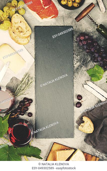 Top view of a blank chalk board for a wine list or menu with Wine and snack set. Variety of cheese, olives, prosciutto meat, baguette slices