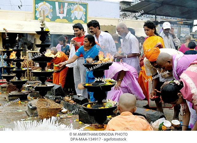 Devotees worshipping and offering coconut; camphor and flowers to Lord Venkateshwara (Balaji) in front of the huge oil lamps  at Tirumala temple; Tirupati ;...