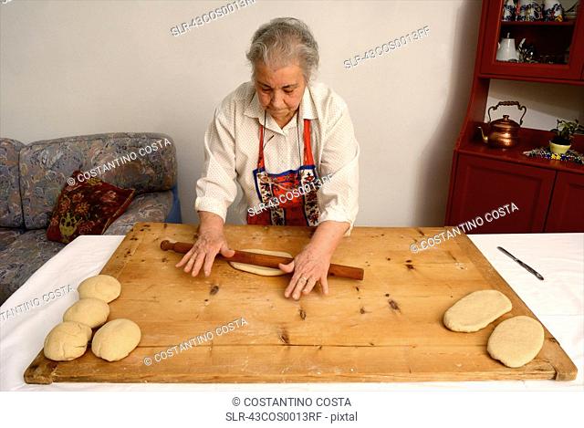 Older woman rolling dough on board