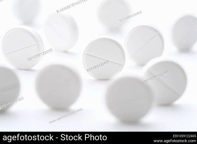 A pile of white pills scattered on a bright white background. Selective focus. Mockup layout, template