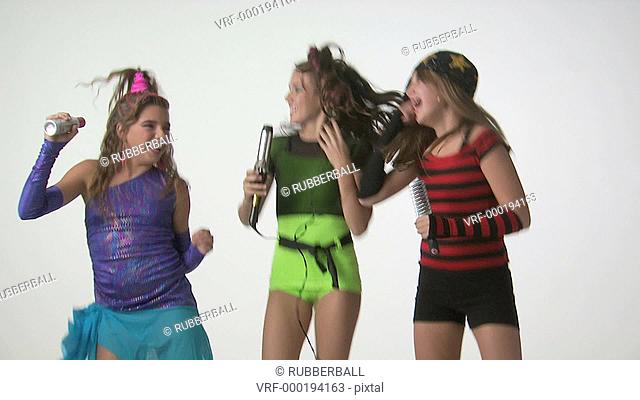 Teenage girls dancing and singing into curling iron and hairbrush