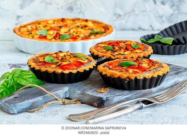 Home mini quiche with chicken, green onions and sweet pepper on an old wooden table
