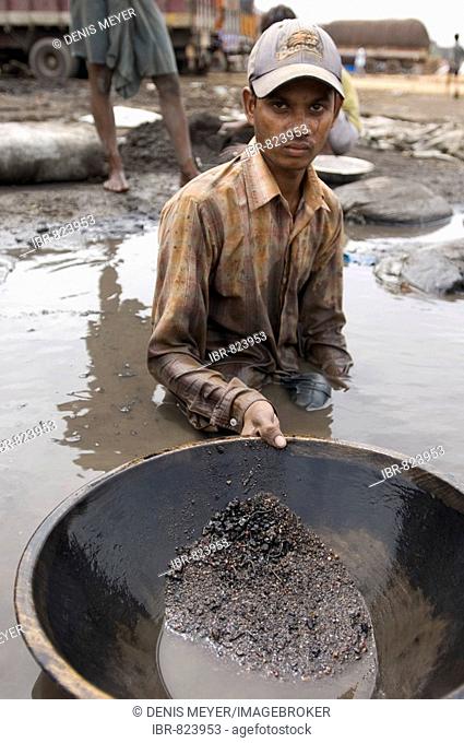 Many slum inhabitants earn their living by recycling industrial waste, this worker is washing poisonous industrial waste for copper, Howrah, Hooghly