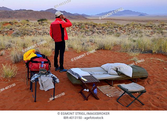 Tourist standing in an open air campsite at Schafberg Camp on Tok Tokkie Trail, Namib Rand Nature Reserve, Namib Desert, Namibia