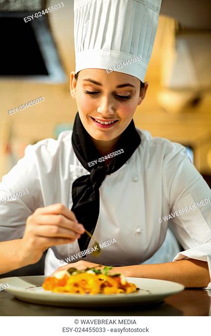 Happy head chef garnishing pasta dish with olive