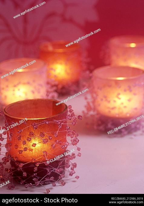 Small tea light candles in glass holders with small decorative stones in pink
