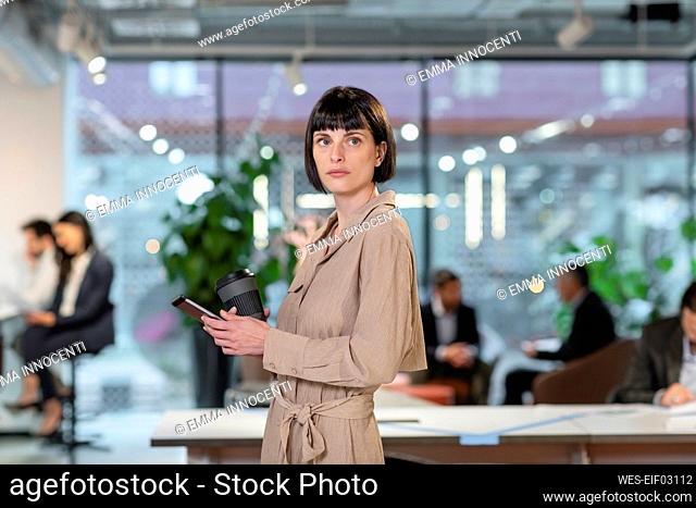 Businesswoman with disposable coffee cup in office
