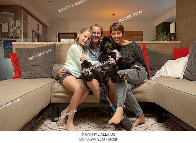 Portrait of parents, daughter and pet dog on sofa