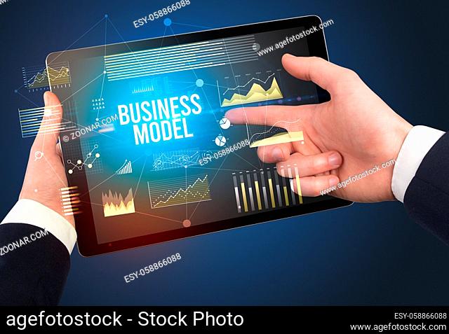 Close-up of hands holding tablet with BUSINESS MODEL inscription, modern business concept