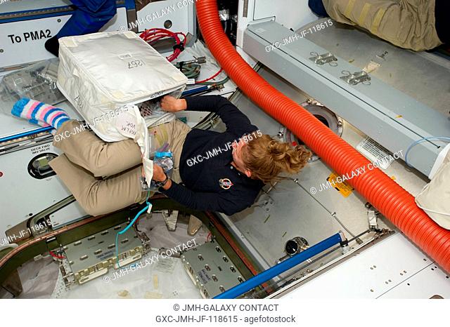 Toting a cargo transfer bag filled with supplies that was carried aboard Raffaello in Atlantis' cargo bay, NASA astronaut Sandy Magnus participates in a very...