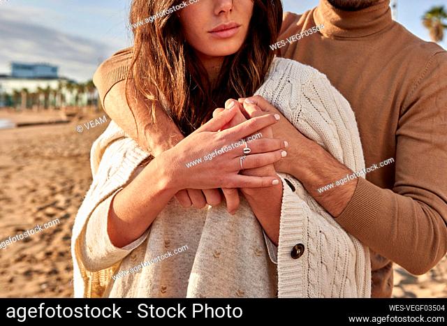 Man embracing woman from behind while standing at beach