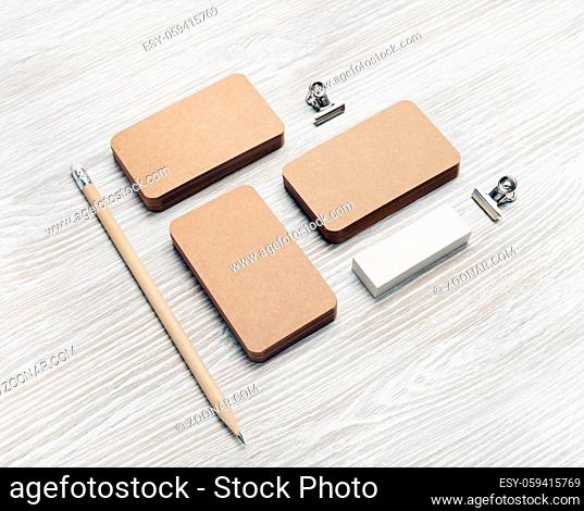 Photo of blank kraft business cards, pencil and eraser on light wooden background. Template for ID