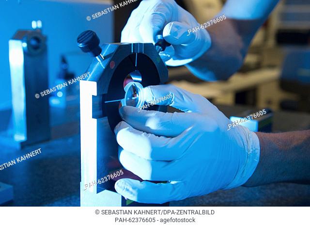 An employee holds an aspheric lens during the tactile measurement in the department for high performance optics of the Carl Zeiss AG in Jena (Thuringia)