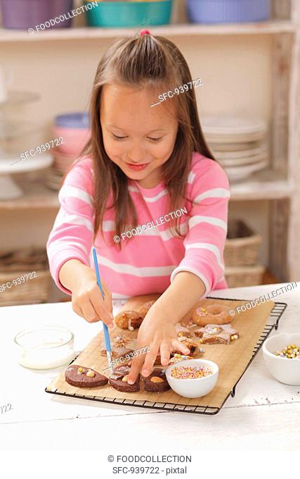 A girl decorating biscuits with icing sugar