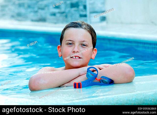 Beautiful blond child in the swimming pool on the summer